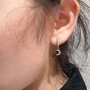 Nahaufnahme Detailansicht eines silbernen Strass Halbmond Anhänger Ohrrings am Ohr.