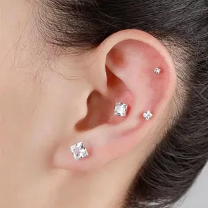 Nahaufnahme von quadratischen Zirkon Ohr-Piercing-Steckern mit funkelnden Kristallen.