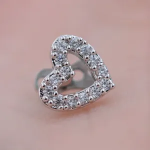 Primo piano dettagliato di un piercing microdermal a forma di cuore con zirconi pavé.