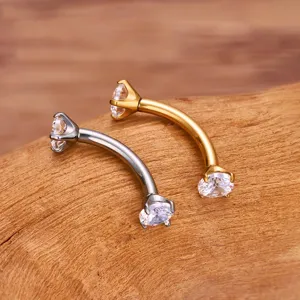 Detail shot of F136 alloy curved barbell eyebrow piercing with dual zirconia stones in gold/silver.