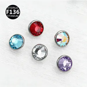 Primer plano detallado de tops de anclaje dérmico de titanio con pedrería de piercing.