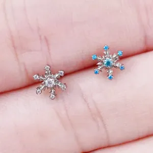 Close-up detail of titanium snowflake piercing studs with sparkling cubic zirconia stones.