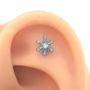 Close-up detail of titanium snowflake cartilage piercing stud with light blue cubic zirconia.