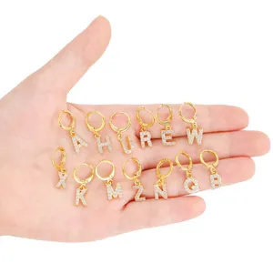 Detail view of gold letter hoop earrings featuring sparkling rhinestone alphabet charms.