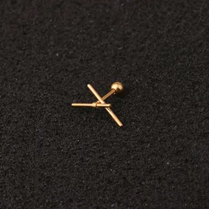 Detailansicht von goldenem Edelstahl Piercing Stab Schmuck mit Kugel und Kreuz Form.