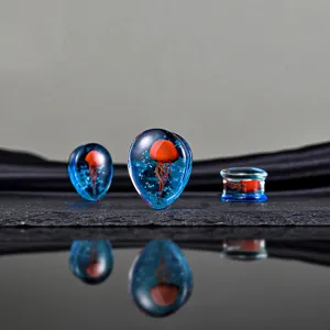 Nahaufnahme Detail blauer Glas Ohrdehner mit lebendigem rotem Qualle Design fur Piercing.