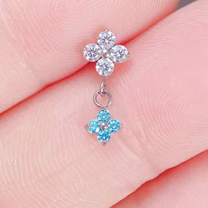 Primo piano dettagliato del piercing in titanio F136 con ciondolo floreale e zirconi.