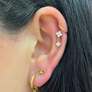 Set orecchini cartilagine in titanio con ciondolo a fiore, vista dettaglio piercing donna.