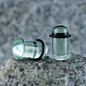 Aquamarinblau Glas Ohr Plugs Tunnel Dehner Piercing Schmuck auf natursteinoberfläche präsentiert.