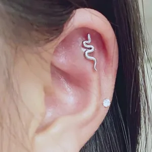Κοντινό πλάνο piercing χόνδρου φιδιού από ανοξείδωτο ατσάλι με λεπτές μεταλλικές λεπτομέρειες.
