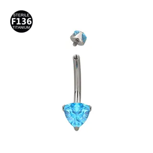 Detalle de piercing para ombligo de titanio, rosca interna con piedra de cristal azul.