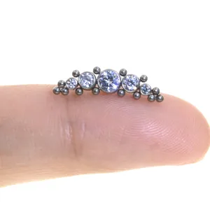 Primo piano dettagliato di gioielli per piercing in titanio con zirconi chiari e perle fini.