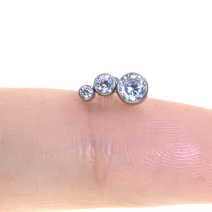 Gioiello per piercing in titanio con zirconi a grappolo dettaglio in primo piano.