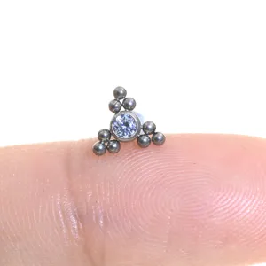 Vista in primo piano del piercing in titanio F136 con zircone brillante e piccole sfere metalliche.