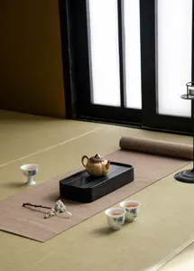 Detalle de juego de posavasos de bandeja de té de madera estilo wabi-sabi con tetera y tazas.