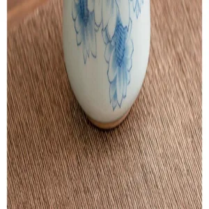Nahaufnahme einer Keramikteetasse mit blauem Sonnenblumenmuster auf Webmatte.