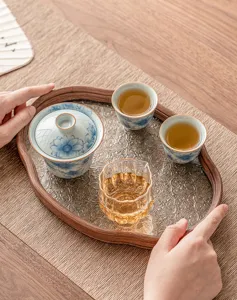 Detail of Chinese kung fu ceramic gaiwan and glass tea tray with blue and white floral pattern.