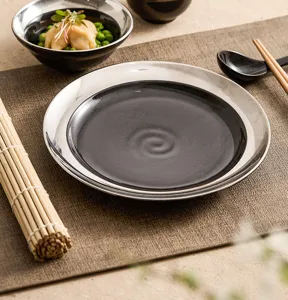 Assiette plate en ceramique noire et argentee, vaisselle ronde elegante pour table de cuisine.