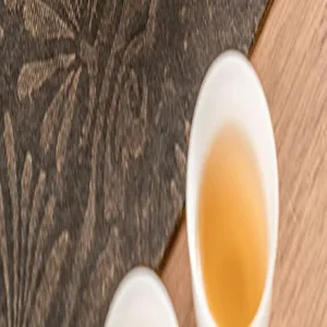 Detailed view of dark tea mat and ceramic tea cup set with warm tea liquid inside.