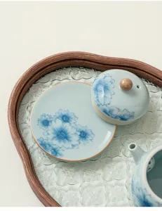 Set di porta coperchio per teiera e sottobicchiere in porcellana blu e bianca con motivo floreale.