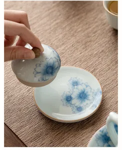 Dettaglio ravvicinato di un supporto per coperchio da tè in ceramica blu e bianca con fiori.