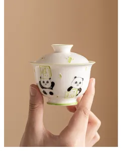 Close-up detail of a white ceramic gaiwan tea cup featuring hand-painted cute panda design.