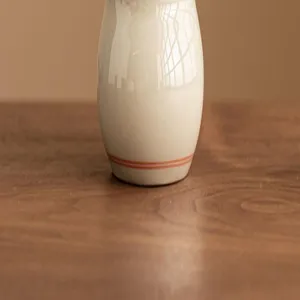 Detailaufnahme des Keramik-Teezubehörs mit handgemalten doppelten Linien auf Holztisch.