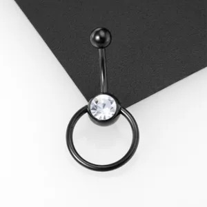 Detalle de cerca de un piercing para ombligo de titanio negro con cristal transparente y anillo.