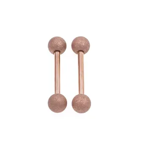Closeup of rose gold frosted barbell nipple rings with textured balls for body piercing.