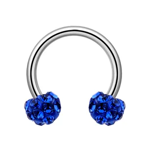 Gros plan détaillé du anneau de piercing fer à cheval en acier avec cristaux bleus brillants.