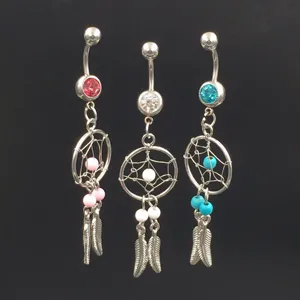 Details of silver belly button ring with dreamcatcher and feather charms, body piercing jewelry.