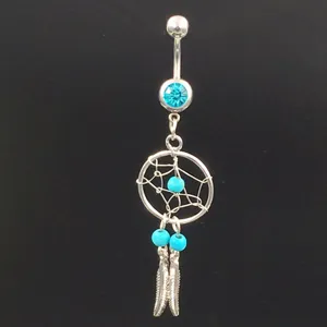Close-up of a stylish navel piercing ring featuring a dreamcatcher motif with turquoise beads.