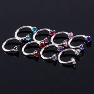 Vue de détail des anneaux de piercing fer à cheval en acier titane avec des zircones multicolores.