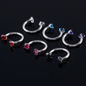 Vue rapprochée et détaillée de piercings fer à cheval en acier avec des zircones colorées.