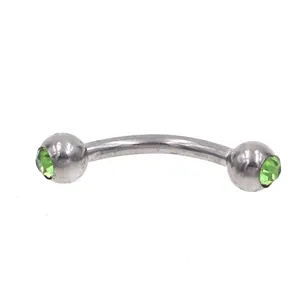 Detailed close-up of 16G stainless steel curved barbell eyebrow ring featuring sparkling green gems.