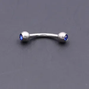 Stainless steel curved barbell eyebrow ring with dual blue crystal gems, 16G piercing jewelry.
