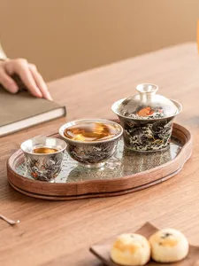 Close-up detail display of elegant silver-plated kung fu tea cup and gaiwan set on wooden tray.