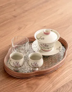 Détail du service à thé gaiwan en céramique peinte avec joli motif et plateau en bois.