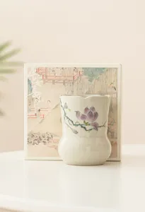 Detaillierte Nahaufnahme eines handbemalten Keramik-Teebehälters mit violetter Magnolie.