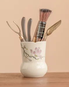 Nahaufnahme der handbemalten Keramik-Teehülse mit Blumenkunst und Tee-Werkzeug-Set.