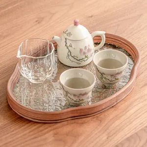 Juego de té de cerámica de magnolia pintado a mano con tetera, tazas y jarra en bandeja de madera.