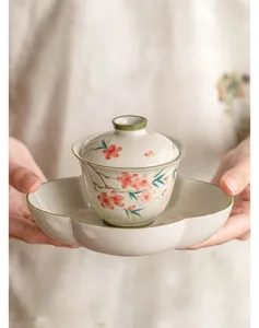 Gros plan détail de l'ensemble de service à thé gaiwan en céramique à fleurs de pêcher.