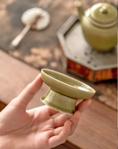 High-footed ceramic teapot lid holder, elegant celadon tea ceremony accessory detail.