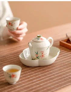 Juego de té de cerámica con hermosos motivos de flor de durazno, tetera y dos tazas.