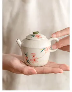 Vista detallada de tetera de cerámica pintada a mano con elegante diseño floral y tapa.