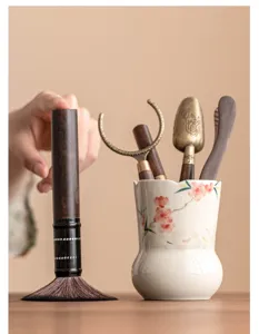 Détail d'ensemble de service à thé fleur de pêcher, porte-thé en céramique et pinceau en bois.