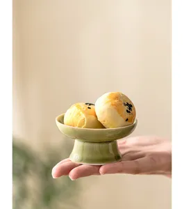 Detailed close-up shot of elegant green ceramic high-footed bowl displaying sweet pastries.