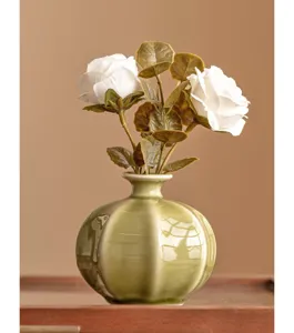 Detail shot of a ceramic mini vase with artificial white roses, elegant desktop decor.