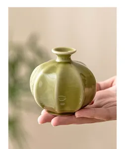 Close-up detail shot of a ceramic mini vase, showcasing its glossy green glaze and elegant shape.