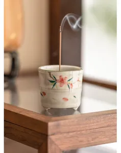 Primo piano del bruciatore di incenso in ceramica dipinto a mano con bastoncino e fumo.